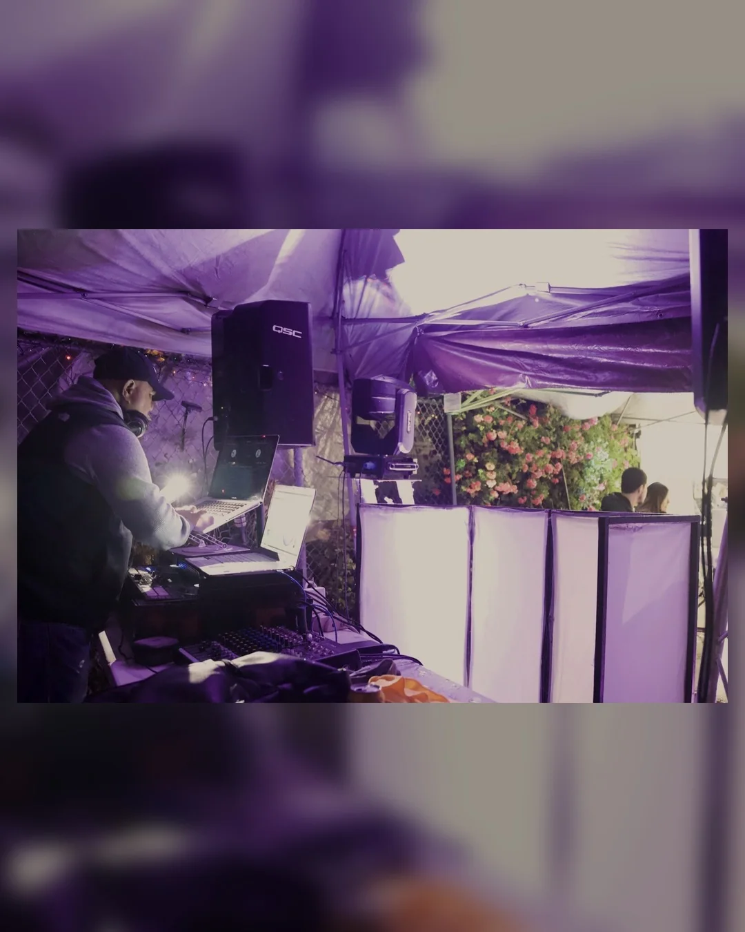 DJ Junny performing under a tent with a full sound and lighting setup